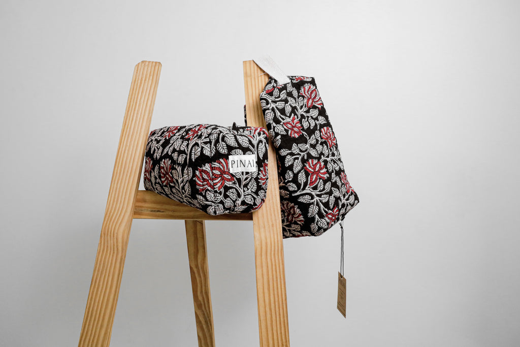 Floral-patterned bags on a wooden stool against a gray background