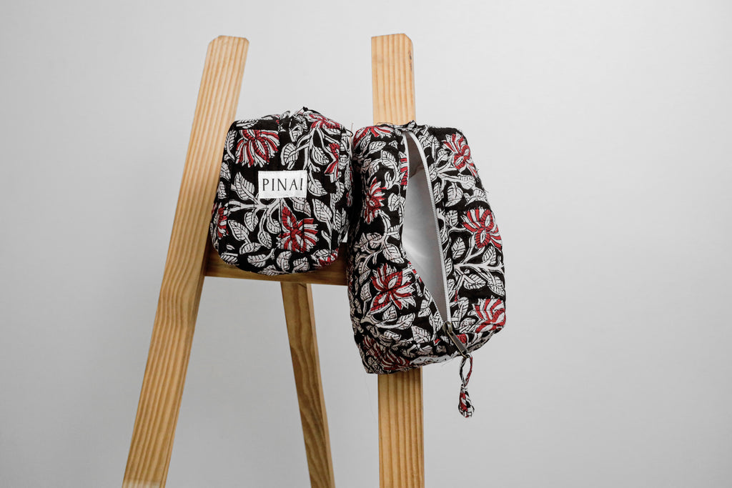 Two floral-patterned bags on a wooden stool against a gray background
