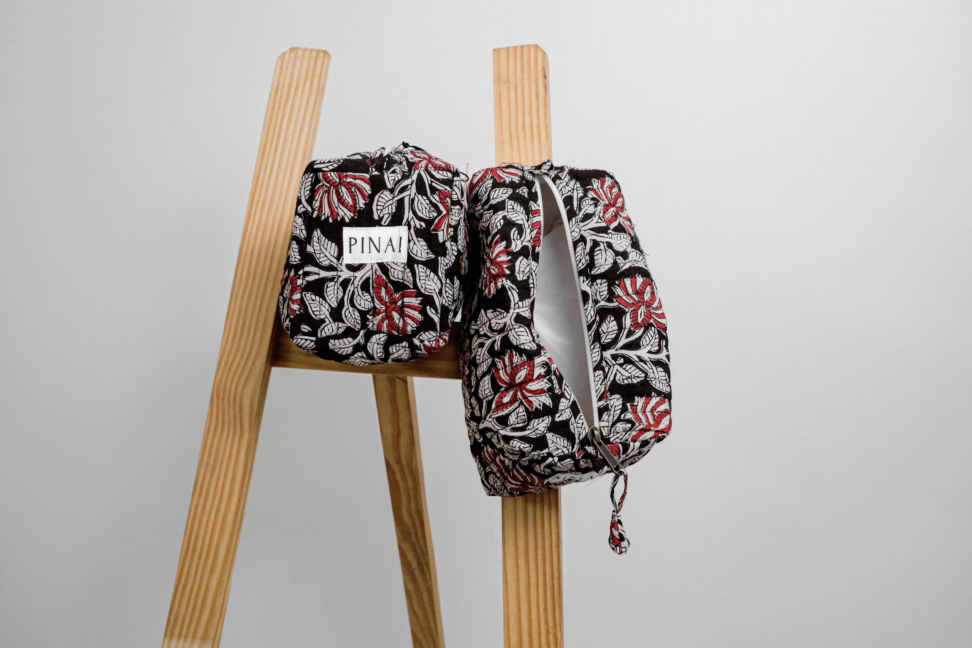 Two floral-patterned bags on a wooden stool against a gray background